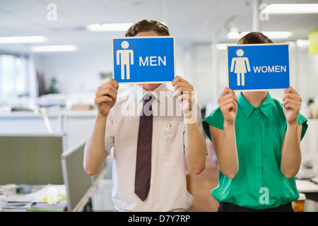 Geschäftsleute, die mit "Männer" und "Frauen" Schildern Stockfoto