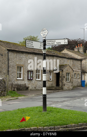 Dorfhalle und alte altmodische Straße Wegweiser an der Kreuzung der Cove Road und Finkle Lane in Malham, North Yorkshire. Stockfoto