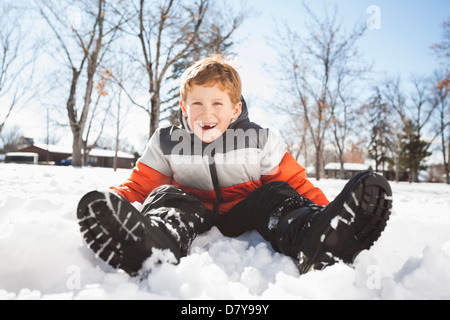 Kaukasische junge sitzen im Schnee im freien Stockfoto