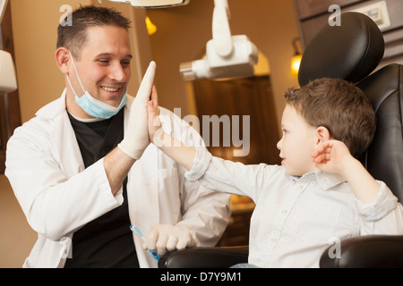 Kaukasische Zahnarzt und junge hohe Fiving im Büro Stockfoto