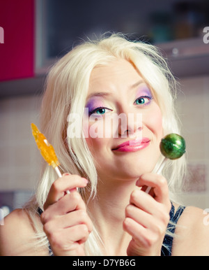 Porträt von einem lächelnden schönen blonde Mädchen mit zwei Bonbons in Händen Stockfoto