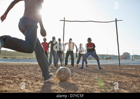 Jungs spielen Fußball zusammen in Schmutz Feld Stockfoto