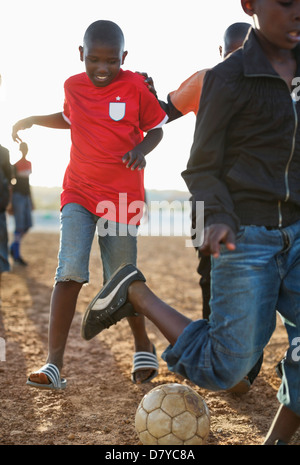 Jungs spielen Fußball zusammen in Schmutz Feld Stockfoto