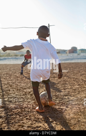 Jungs spielen Fußball zusammen in Schmutz Feld Stockfoto