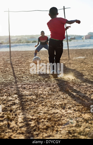 Jungs spielen Fußball zusammen in Schmutz Feld Stockfoto