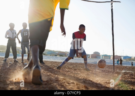 Jungs spielen Fußball zusammen in Schmutz Feld Stockfoto