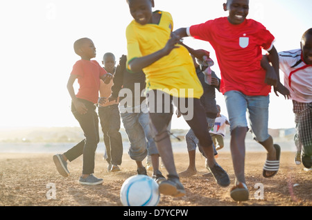 Jungs spielen Fußball zusammen in Schmutz Feld Stockfoto