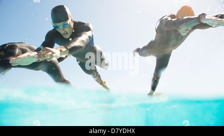 Triathleten in Neoprenanzüge laufen ins Meer Stockfoto