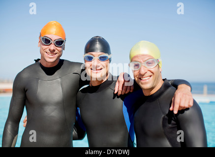 Triathleten in Neoprenanzüge lächelnd zusammen Stockfoto