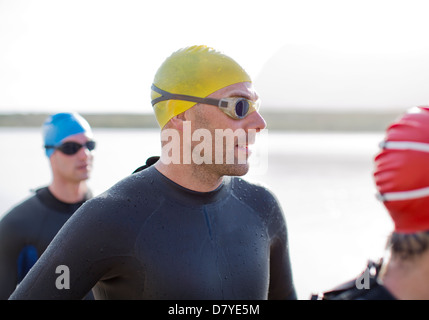 Triathleten in Neoprenanzüge stehen am Strand Stockfoto