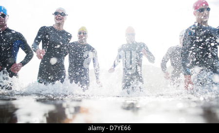 Triathleten in Neoprenanzüge in Wellen laufen Stockfoto