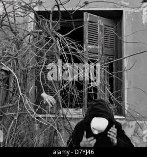 Maskierte Figur in schwarz und überwucherten abgestorbene Pflanzen. Schwarz und weiß, Bewegungsunschärfe. Stockfoto