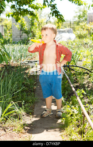 Entzückender kleine Junge stehend in der Sonne auf einen Pfad im Gemüsegarten in Gedanken versunken Stockfoto