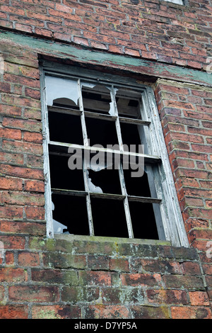Alte Holzfenster setzen in einem roten Backsteingebäude mit Glasscherben Stockfoto