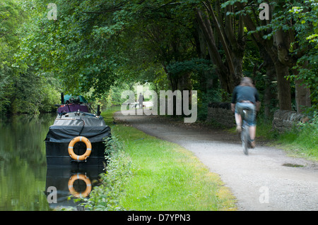 Ruhigen, malerischen, ländlichen, von Bäumen gesäumten Strecke von leinpfad mit Boote & Mann Radtouren entlang - Leeds Liverpool Canal, Saltaire, Yorkshire, England, UK. Stockfoto