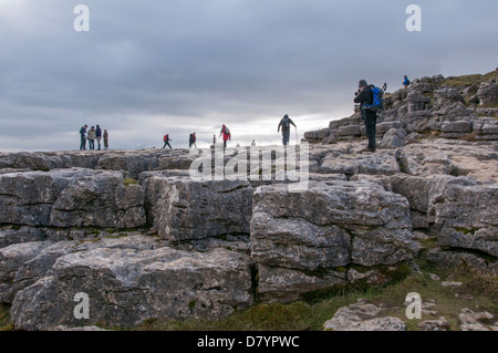 Leute stehen & gehen auf die Berggebiete limestone Pavement, spektakulären, natürlichen Funktion an der Spitze der Malham Cove - Malhamdale, Yorkshire Dales, England, UK. Stockfoto