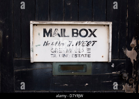 In der Nähe von Alte hölzerne Tafel, die Position der Mailbox für Herr und Frau West auf Holz Tür mit abblätternder Farbe - in der Nähe von Skipton, England, GB, UK montiert. Stockfoto