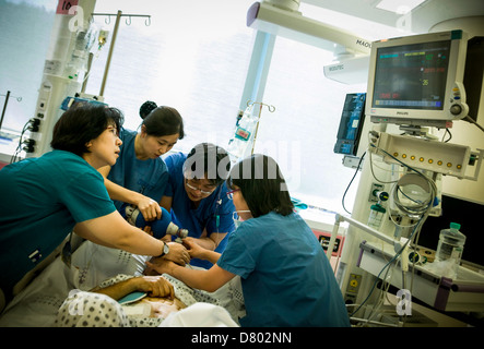 Medizinisches Personal verwenden ein Sauerstofftank, um den Patienten wieder zu beleben, die in Narkose in der Intensivstation ist. Stockfoto