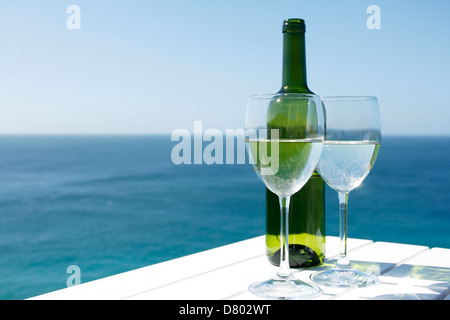 Gläser Wein auf einem weißen Tisch durch den Ozean. Stockfoto