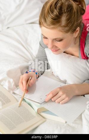 Teenager-Mädchen konzentriert sich auf die Untersuchung von Buch auf Bett liegend Stockfoto