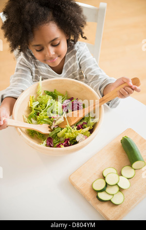 Afroamerikanische Mädchen warf Salat am Tisch Stockfoto