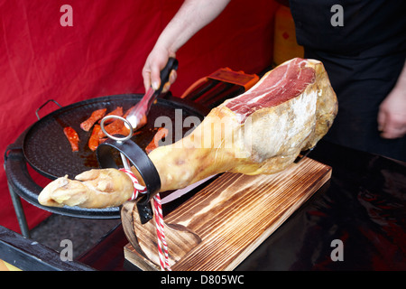 Serrano-Schinken auf ein Stativ und Mann Kochen Chorizo Wurst in ein outdoor-event Stockfoto