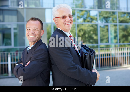 Zwei glückliche Geschäftsleute auf einander Rücken an Rücken gelehnt Stockfoto
