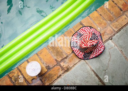 Ein Hut mit amerikanischer Flagge und eine Styroporschale lagen neben einer Schwimmvorrichtung in einem Swimmingpool. New Orleans, LA. Stockfoto