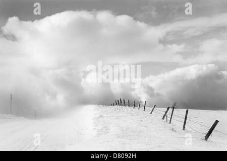 Wolken und Holzzaun in Schneelandschaft Stockfoto
