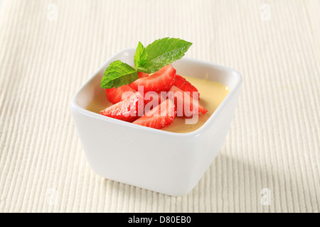 Kleine Schüssel mit Vanillepudding mit Erdbeeren garniert Stockfoto