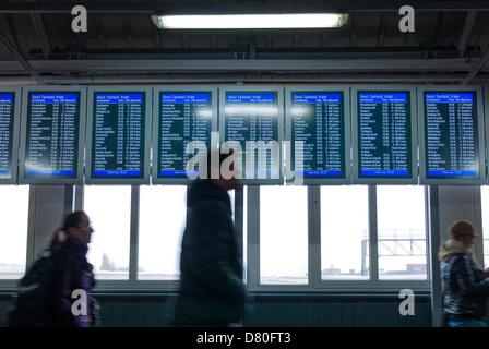 Passagiere, die zu Fuß durch elektronische Zuges anzeigen Board in Clapham Junction Stockfoto