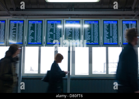 Passagiere, die zu Fuß durch elektronische Zuges anzeigen Board in Clapham Junction Stockfoto
