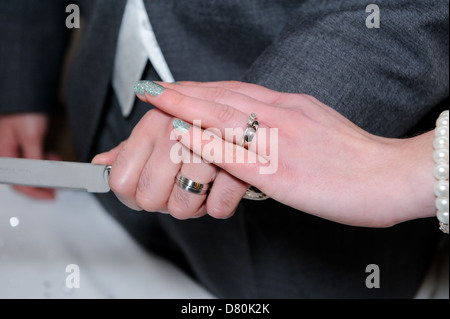 Braut und Bräutigam Hände close-up Schneiden Kuchen zeigt Ringe detail Stockfoto