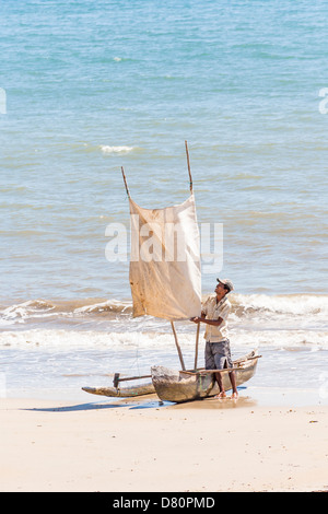 Nosy Be, Madagaskar - Fischer mit ausgegraben Kanu und primitiven Segel am Ufer Meeres Stockfoto