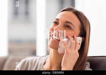 Hübsche junge Frau mit weißen Handy zu Hause lächelnd