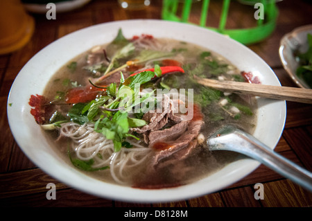 PROVINZ XIENG KHOUANG, Laos — Eine dampfende Schüssel Lao Pho Nudelsuppe mit duftender Brühe, Reisnudeln, frischen Kräutern und Fleischscheiben wird in einem traditionellen Restaurant in Vientiane serviert. Dieses beliebte laotische Gericht ist ein Grundnahrungsmittel in der Küche des Landes und bietet eine angenehme und geschmackvolle Mahlzeit, die sowohl von Einheimischen als auch von Besuchern genossen wird. Stockfoto