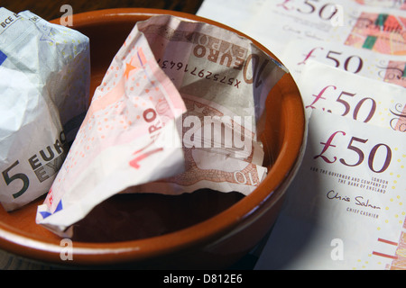 10 und 5 Euro-Banknoten in einer braunen Schale auf Sterling £50 Notizen vermasselt Stockfoto