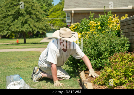 Ein kaukasischer Mann, 27 Jahre alt, breitet sich in einem Bett mit Sträuchern Mulch. Oklahoma, USA. Stockfoto