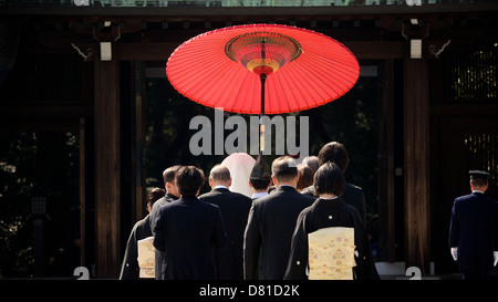 Japanische traditionelle Shinto Hochzeit im Meiji-Schrein mit Bright Red Gifu Regenschirm und Gefolge von Familie und Freunden Stockfoto