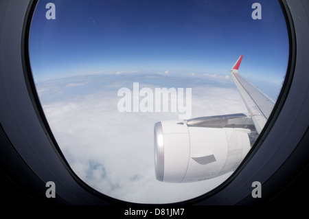 Wolken und Himmel gesehen durch Fenster eines Flugzeugs Stockfoto
