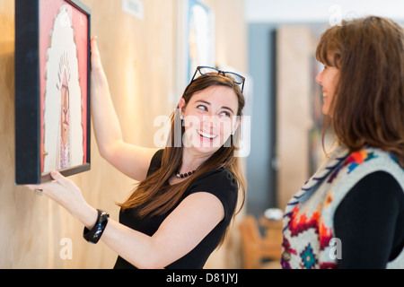 Frauen, die Gemälde an der Wand hängen Stockfoto