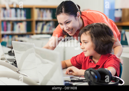 Lehrer und Schüler mit Laptop in der Bibliothek Stockfoto