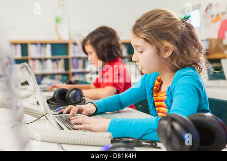 Kaukasische Kinder mit Notebooks in der Bibliothek Stockfoto