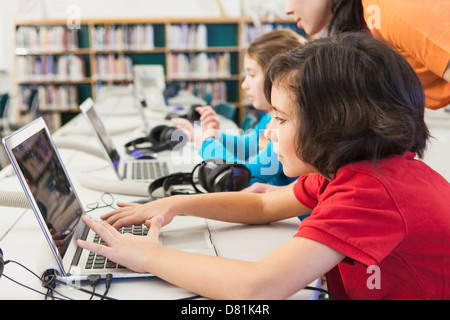 Kaukasische Kinder mit Notebooks in der Bibliothek Stockfoto