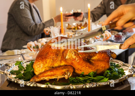 Paar Toasts auf formale Wohn Esszimmer Tisch gedeckt für Thanksgiving Essen während Türkei ist geschnitzt, USA Stockfoto