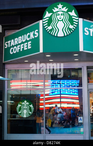 Elektronische US-Flagge spiegelt sich im Fenster ein Starbucks-Café auf dem Times Square. Stockfoto