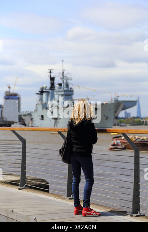 Frau betrachten HMS Illustrious in Greenwich, London England Stockfoto