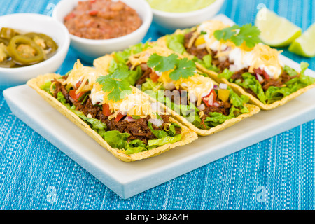 Rindfleisch Tacos - Hackfleisch-Taco-Schalen garniert mit Salsa, saure Sahne und geriebenem Käse. Stockfoto