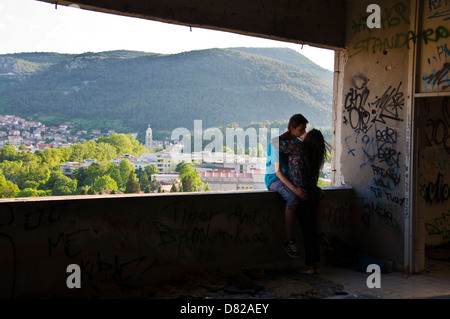 Paar Kuss im Graffiti bedeckt Krieg beschädigt Stara Banka Staklena Gebäude In Mostar Stockfoto