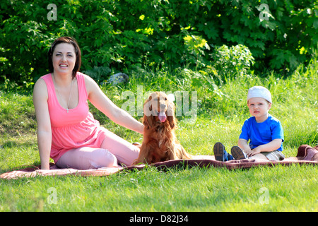 Yong-Mutter mit Kleinkind und Hund sitzt am rad auf Natur Stockfoto